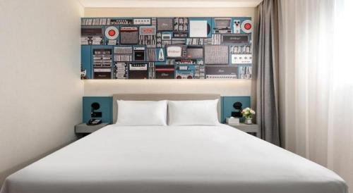 a bedroom with a white bed and a wall of appliances at ibis Dongguan Dongcheng in Dongguan