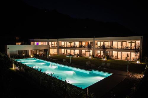 a large building with a swimming pool at night at Residence & Sportlodges Claudia in Plaus