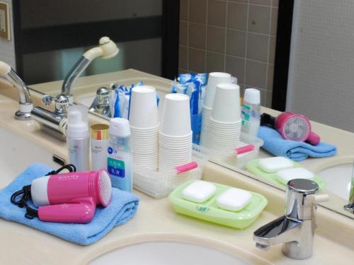 a bathroom counter with a sink with toothbrushes and toothpaste at Minshuku Shima in Kaga