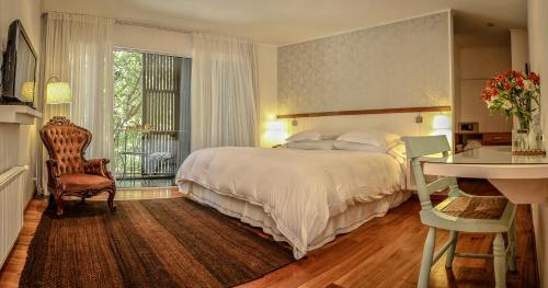 a bedroom with a bed and a desk and a window at Hotel Casa Zapallar in Zapallar