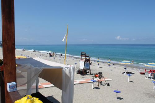 a beach with chairs and umbrellas and the ocean at Hotel South Paradise in Palmi