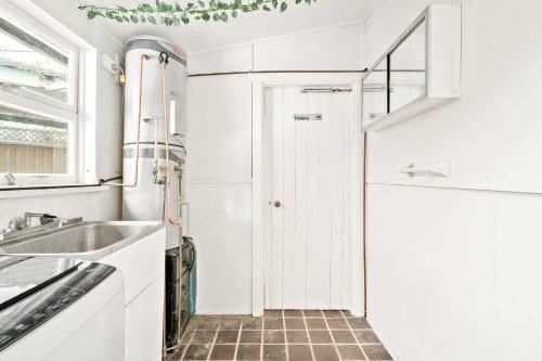a white kitchen with a sink and a window at Simple Single Room - Serene Spot at Peakhurst - Shared Bathroom in Peakhurst