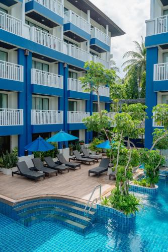 an exterior view of a hotel with chairs and umbrellas at Blue Tara Hotel Krabi Ao Nang in Ao Nang Beach