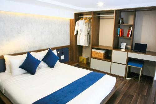 a bedroom with a bed with blue and white pillows at KunKin Garden Aparthotel in Ho Chi Minh City