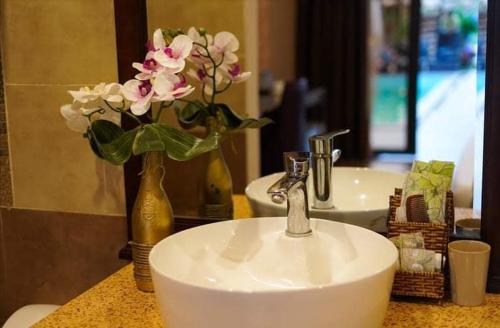a bathroom with a sink and a vase with flowers at MILAN Boutique Garden in Vung Tau