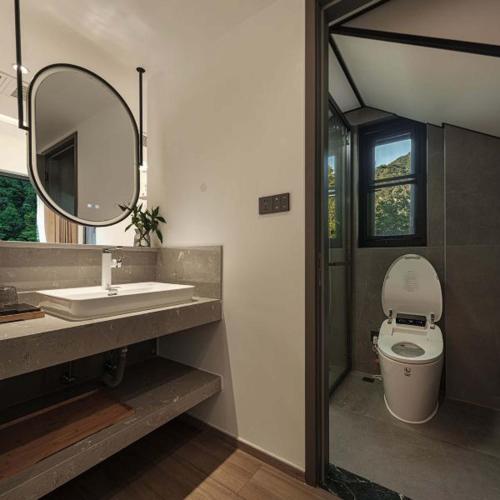 a bathroom with a sink and a toilet and a mirror at Anji Xishan Linyu Chinese-style Spring · Stream Tracing · Vacation Boutique Inn in Anji