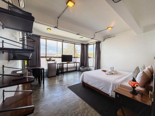 a bedroom with a bed and a living room with a desk at AV Suites in Puerto Galera
