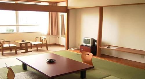 a living room with a table and a tv at Sunshine Shirako New in Shirako