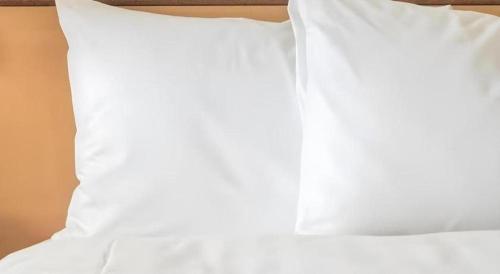a white pillow sitting on top of a bed at RH Hotel Sibu in Sibu