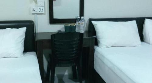 a bedroom with a desk and a chair between two beds at Power Hotel in Georgetown