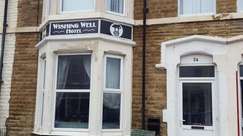 a building with a sign for a wishing wall hotel at Wishing Well Guest House in Blackpool