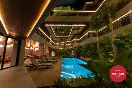 una piscina coperta in un edificio con sedie e piante di Piece Lio from Japan Managed by H Hospitality Group a El Nido
