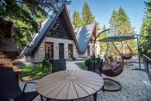 una mesa con sombrilla frente a una casa en Forest Whisper SPA, en Žabljak