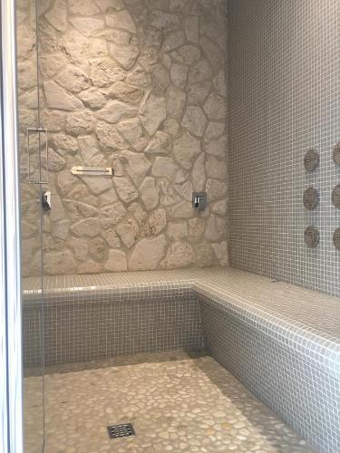 a bathroom with a shower with a stone wall at Il Girasole in Marti