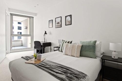 a white bedroom with a large bed and a window at Luxury Stay Near Grand Prix Track in Melbourne