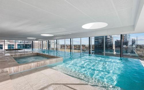 a large swimming pool in a building with windows at Luxury Stay Near Grand Prix Track in Melbourne