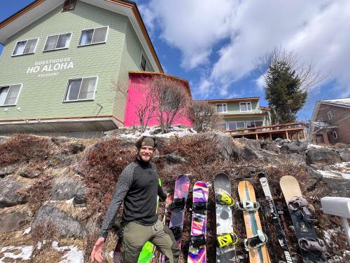 a man standing in front of a pile of snowboards at Guesthouse HOALOHA 4 SEASONS in Chino