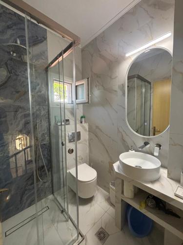 a bathroom with a shower and a toilet and a sink at Moriel Seaside Homes Suites in Elia