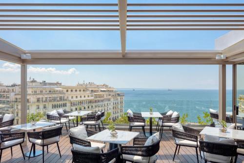a restaurant with tables and chairs and a view of the ocean at Electra Palace Thessaloniki in Thessaloniki