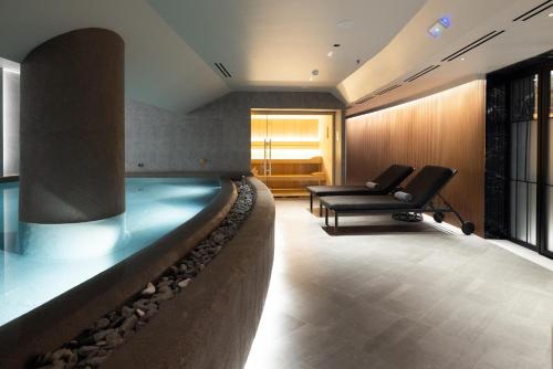 a pool in a room with a couch and a chair at Electra Palace Thessaloniki in Thessaloniki