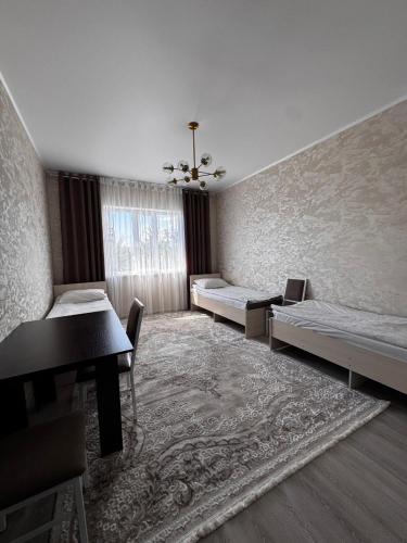 a room with two beds and a table and a window at Cholpon Guest House & Hostel in Toktogul