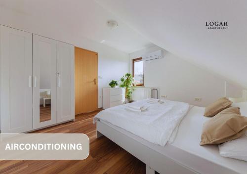 a white bedroom with a large bed in a room at LOGAR Apartments in Preddvor