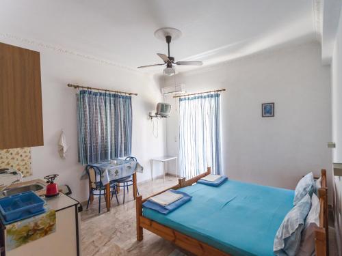 a bedroom with a blue bed and a kitchen at Pension Vienna in Methana