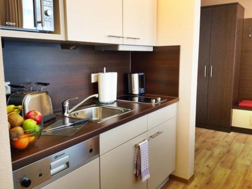 a kitchen with a sink and a bowl of fruit on the counter at Apartmenthotel Quartier M in Leipzig