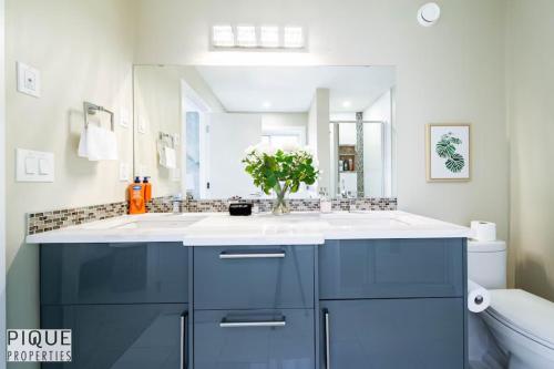 une salle de bain avec un lavabo bleu et un miroir dans l'établissement Summer Haven - HotTub - FireTable - KingBed - BBQ - Sleeps8, à Edmonton