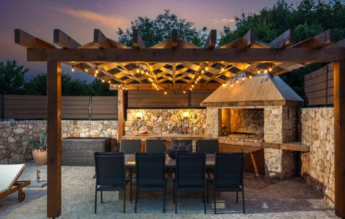 an outdoor kitchen with a table and a fireplace at Villa LuLu kamena villa s maslinikom otok Krk Dobrinj selo Gostinjac in Krk