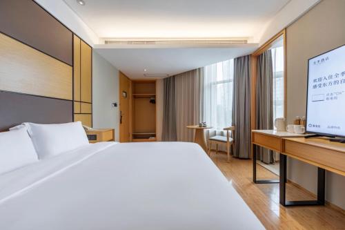 a bedroom with a bed and a desk with a computer at Ji Hotel Shanghai Changshou Road - Near Metro Line 13&14,Free Luggage Storage,English Service in Shanghai