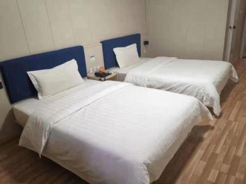 two beds sitting next to each other in a room at 7 Days Inn Changzhou Yancheng Technology Metro Station in Changzhou