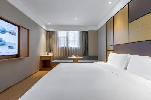 a hotel room with a large bed and a flat screen tv at Ji Hotel Shanghai Changshou Road - Near Metro Line 13&14,Free Luggage Storage,English Service in Shanghai