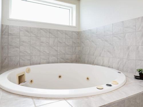 a white bath tub in a bathroom with a window at 8 person holiday home in Ringkøbing-By Traum in Ringkøbing