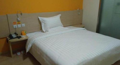 a bedroom with a large white bed and a night stand at 7 Days Inn Suzhou Wangting Pearl Commercial Plaza in Suzhou