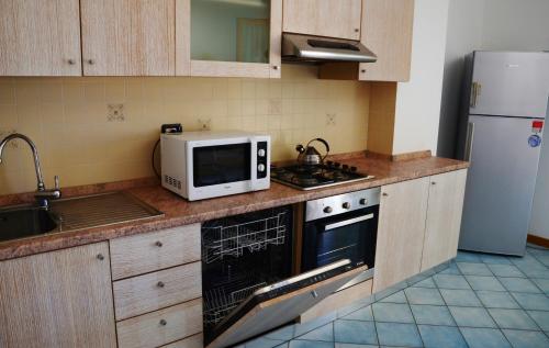 a kitchen with a microwave and a stove and refrigerator at Residence Buganvillea in Alghero