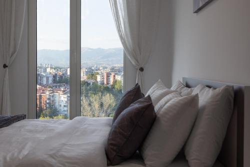 a bed with pillows in front of a large window at Cevahir Sky City 2BR Family APT, Fitness & Spa in Skopje