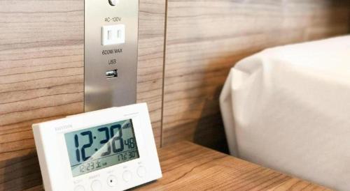 a clock sitting on a table next to a bed at KEIKYU EX INN Haneda Innovation City 2 minutes walk from HICity Exit of Tenkubashi Station in Tokyo