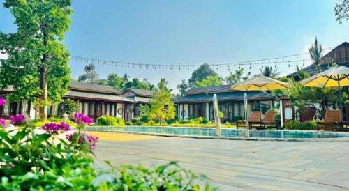 a resort with a swimming pool and chairs and umbrellas at Jun's Home in Buon Ma Thuot
