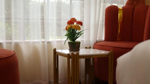 a vase with flowers on a table next to a window at LIA Hotel & Training Centre in Nairobi