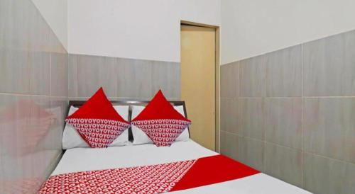 a bedroom with a bed with red and white pillows at Hotel O Benteng Kost in Jambi