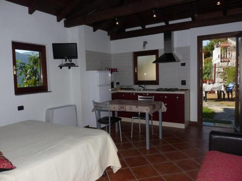 a bedroom with a bed and a table and a kitchen at Il Basciutin in Pettenasco