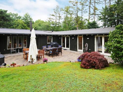 a house with a patio with a table and a umbrella at 6 person holiday home in Gilleleje in Gilleleje