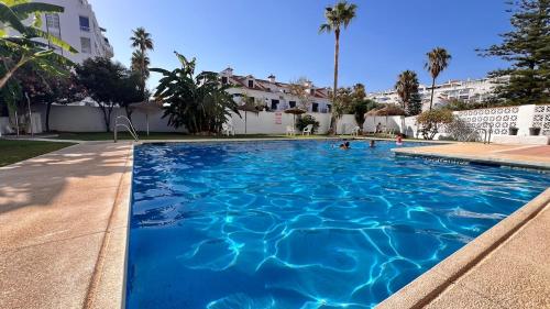 a large swimming pool with blue water at Magnífico Ático 4 hab frente a la playa con piscinas parking incluido por keywise in Fuengirola