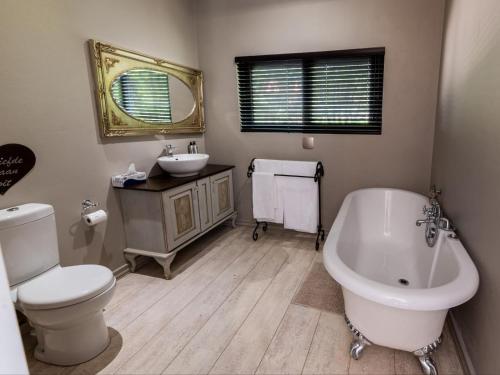 a bathroom with a tub and a toilet and a sink at La Serenita @ Migdash in Hartbeespoort