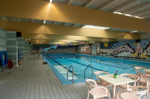 a large swimming pool with chairs and a tables and chairs at Recreatiepark de Koornmolen in Zevenhuizen