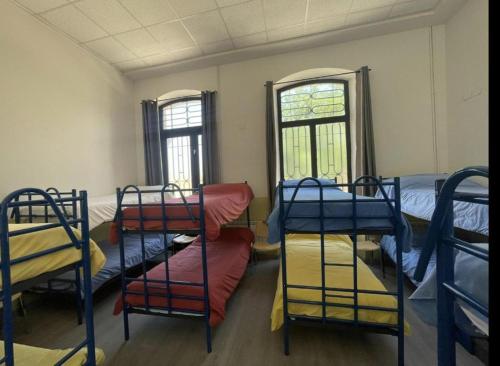 a room with three bunk beds and two windows at El Vagón Bar-Albergue Béjar in Béjar
