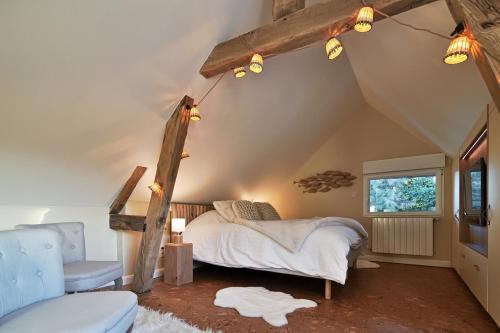 a bedroom with a bed and a chair and a window at Le Jardin des Hespérides - Piscine intérieure, Jacuzzi et Sauna in Fourmetot