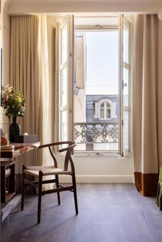 a room with a table and a chair and a window at Hotel Palais Bourbon in Paris
