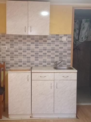 a kitchen with white cabinets and a sink at sobe DALE in Subotica